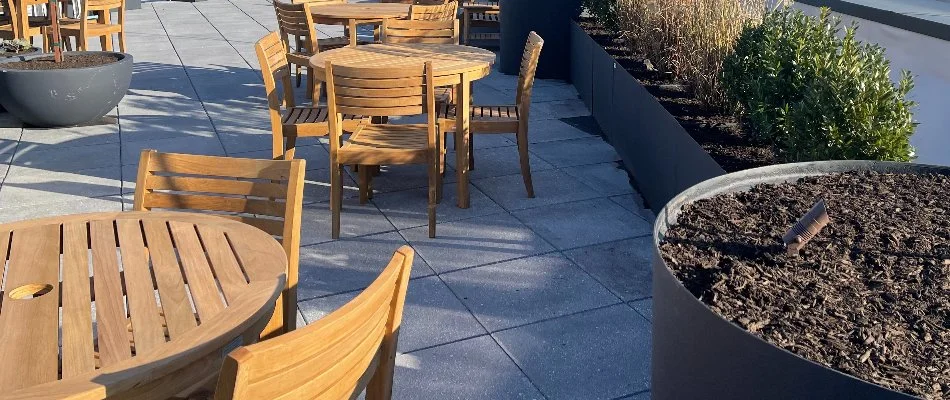 Wooden tables and chairs on a concrete paver patio in Alpine, NJ.