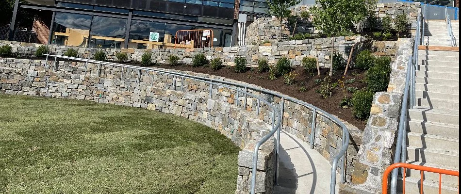 Stone retaining wall with landscape bed and walkway.